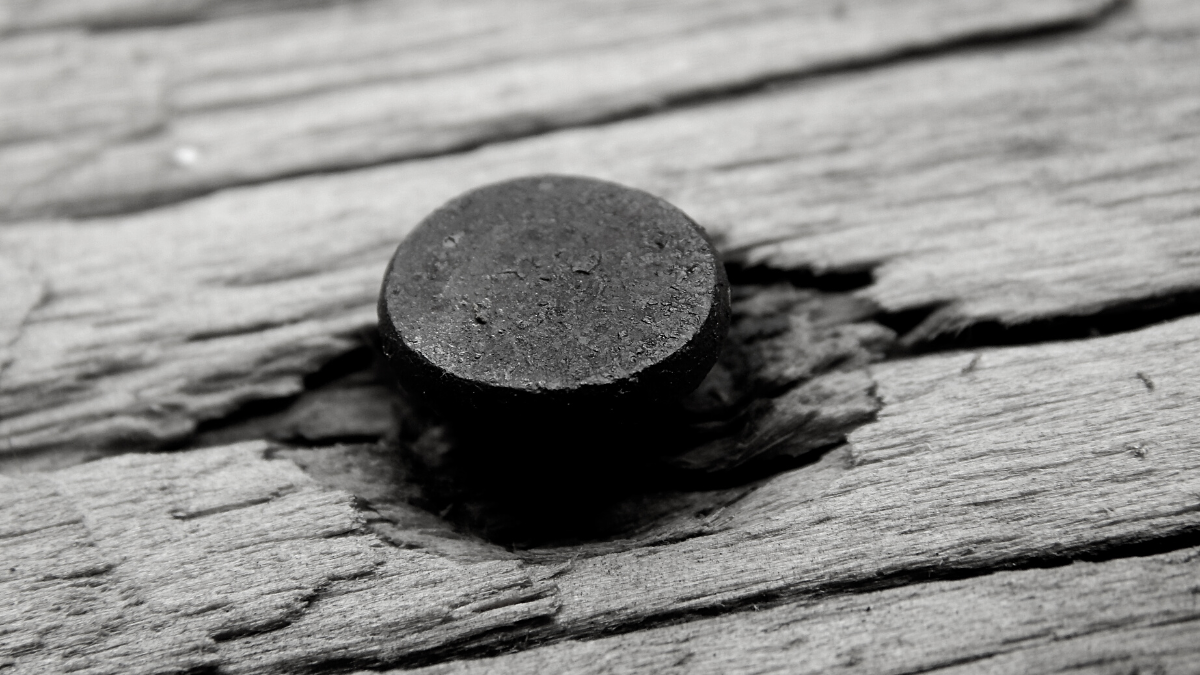 A grayscale image of a nail in wood